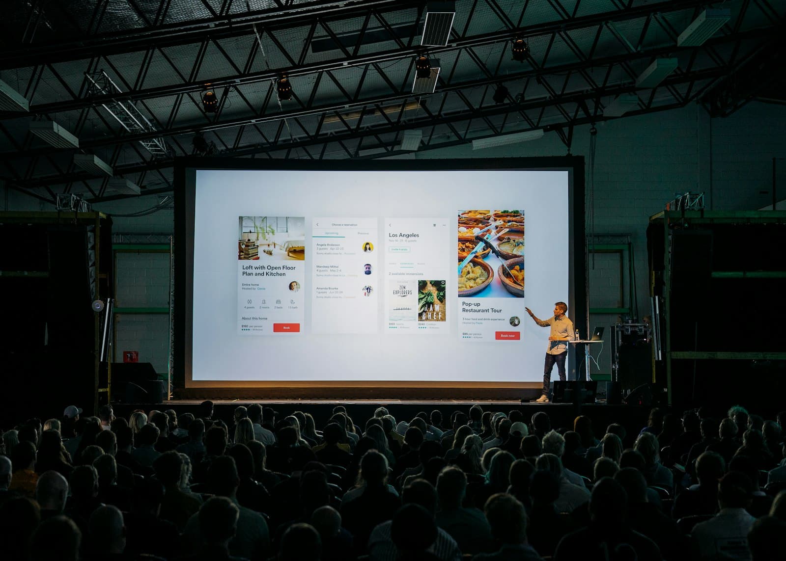 A speaker addressing a conference from a lit stage.