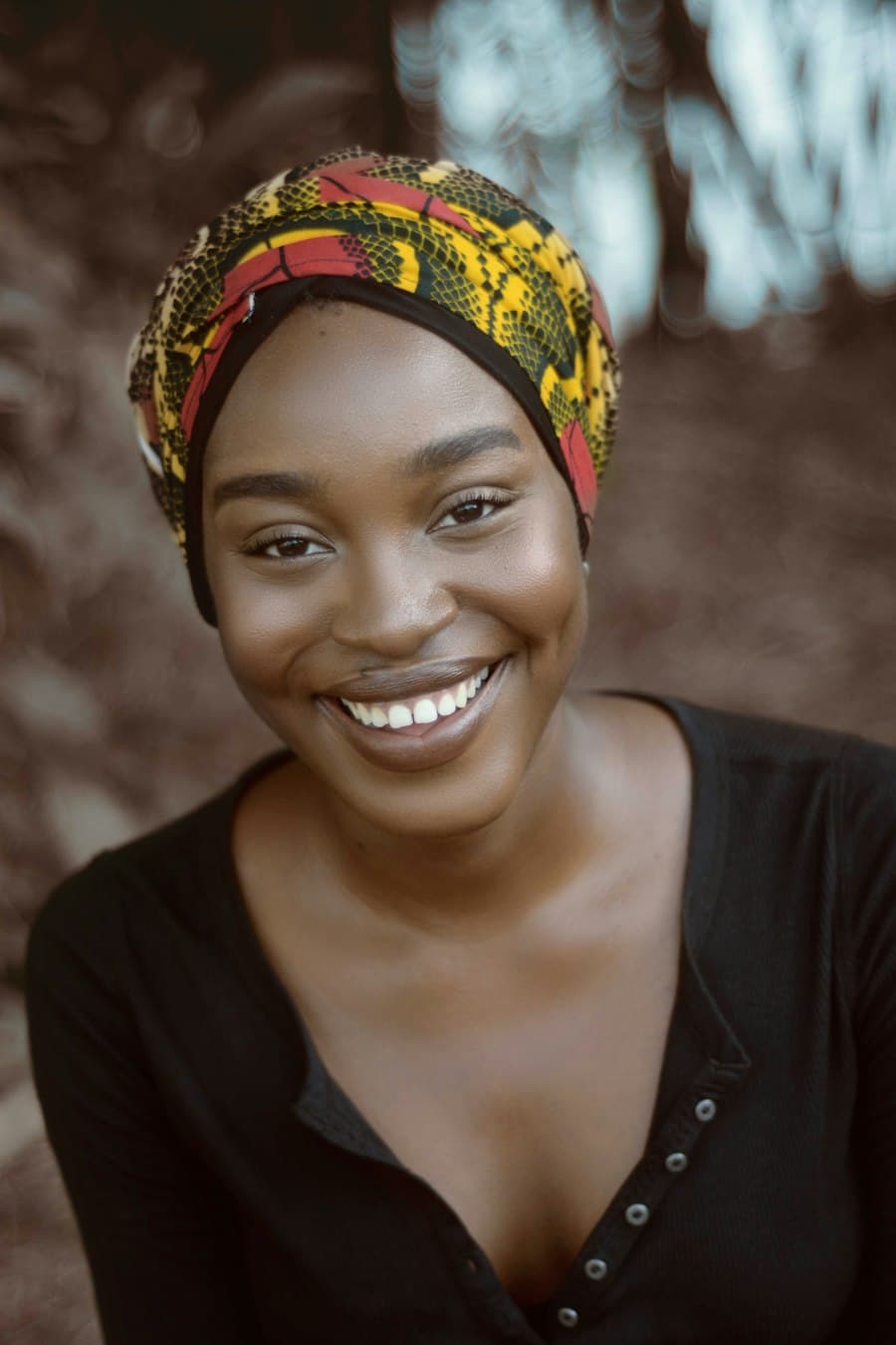 Illustrative portrait of a smiling woman wearing a patterned headwrap, used for a sample speaker profile.