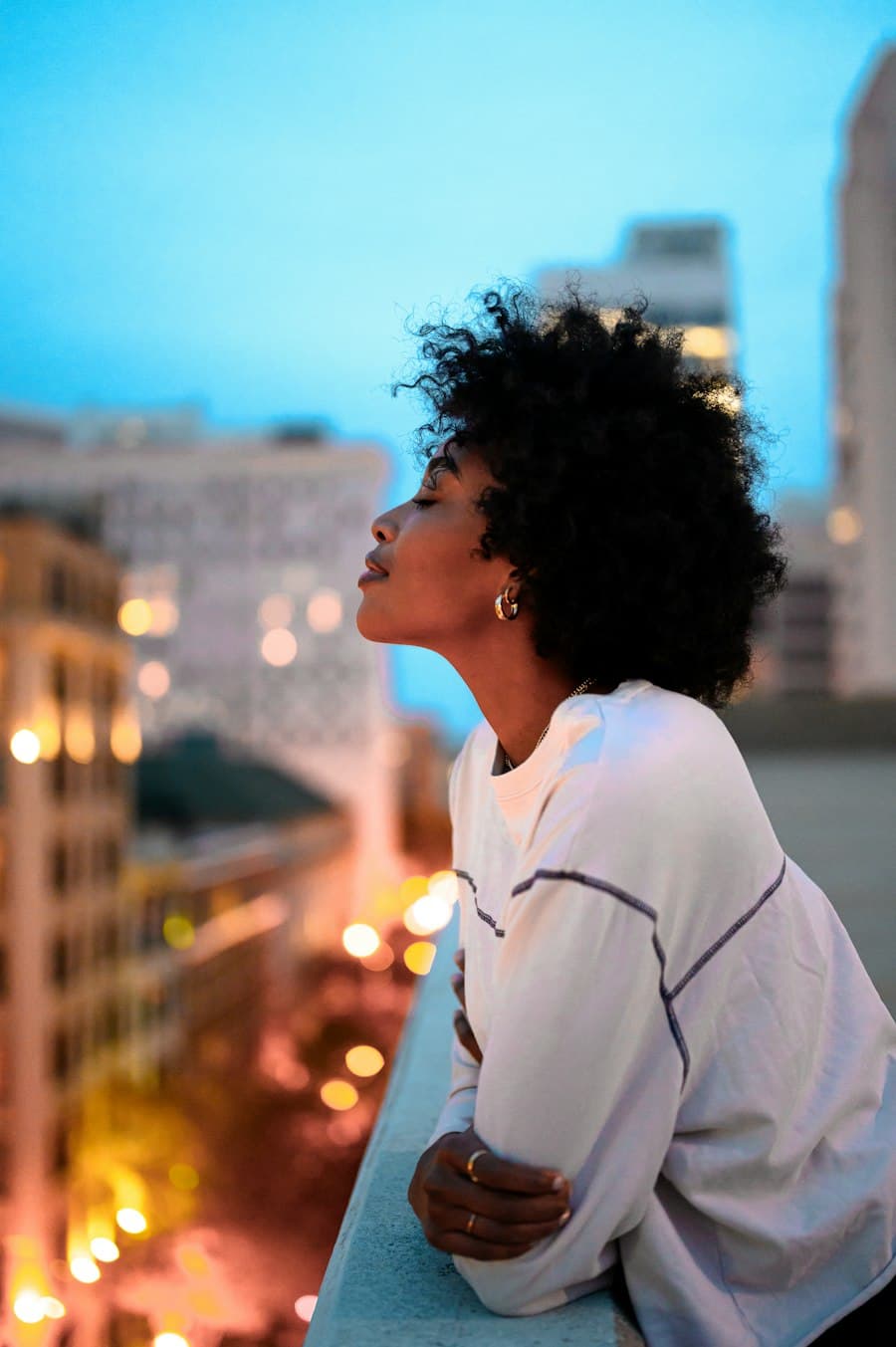 Illustrative portrait of a woman in profile on a balcony at dusk, used for a sample speaker profile.