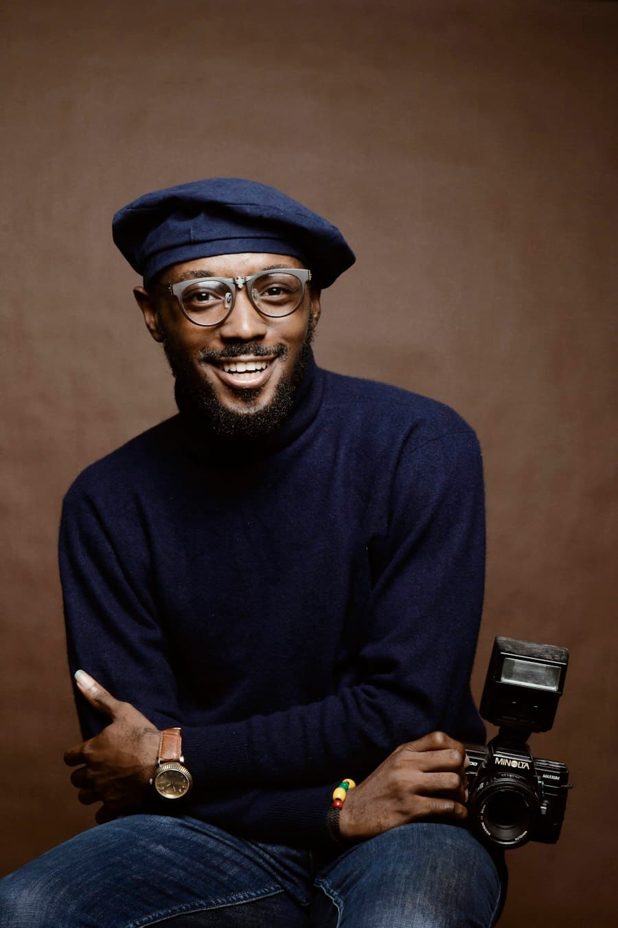 Illustrative portrait of a man in a navy beret holding a camera, used for a sample speaker profile.